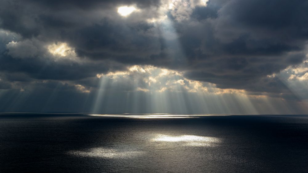 Sun-breaking-through-grey-clouds-over-the-sea